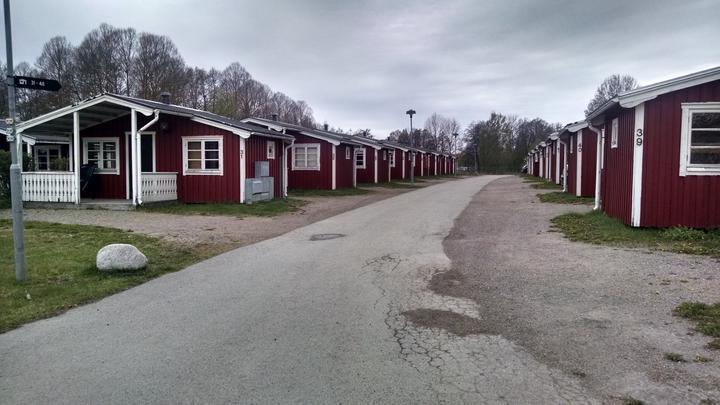 paved road through a row of uniform red and white single-story shelters